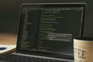 Developer working on code with laptop showing programming interface and code editor