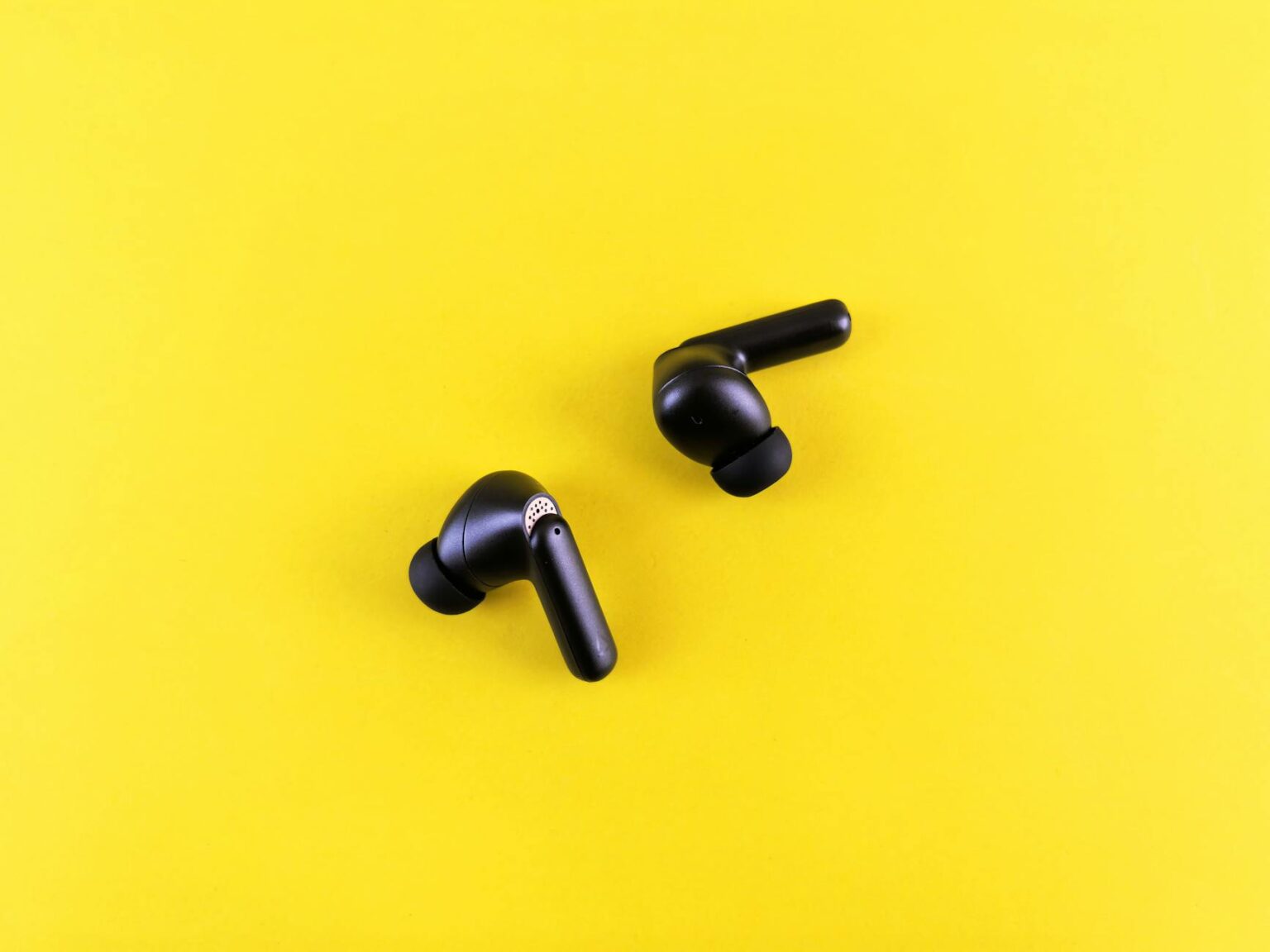 Modern wireless earbuds with charging case on clean white surface