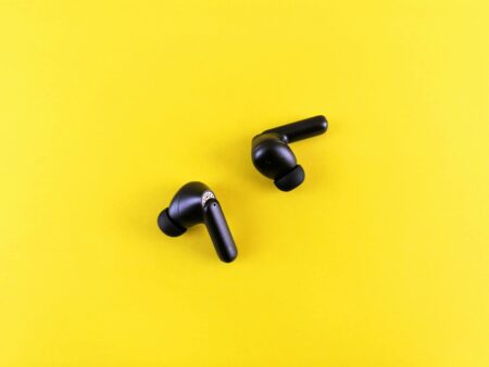 Modern wireless earbuds with charging case on clean white surface