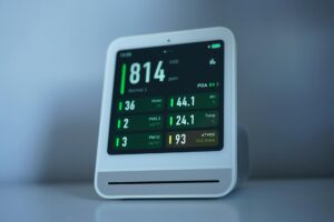 Modern smart thermostat mounted on white wall showing digital temperature display