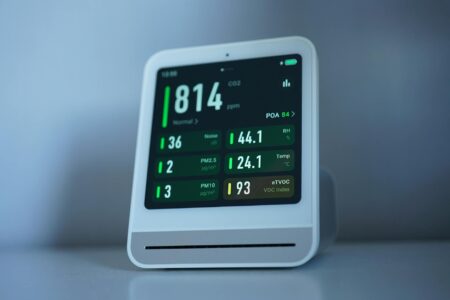 Modern smart thermostat mounted on white wall showing digital temperature display