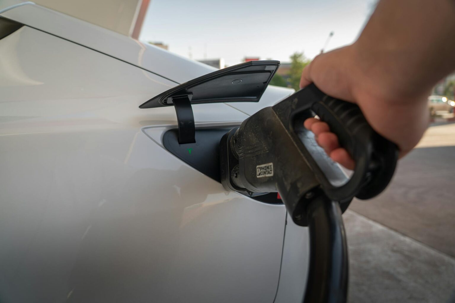 Electric vehicle being charged at a charging station with cable connected