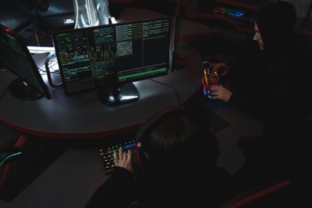 A developer managing security credentials on a laptop with a team in the background