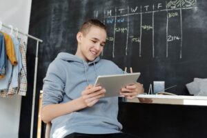 Person writing on an e-ink tablet with a stylus on a desk