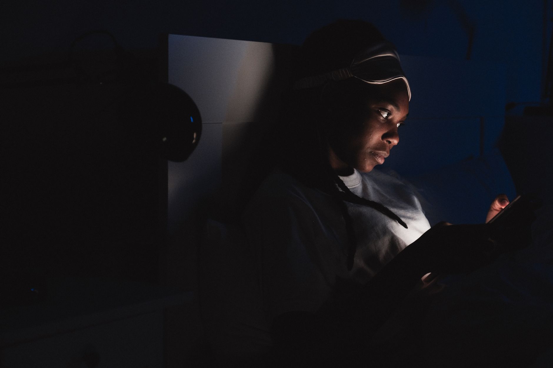 Person reading on a tablet in low light, representing digital library access